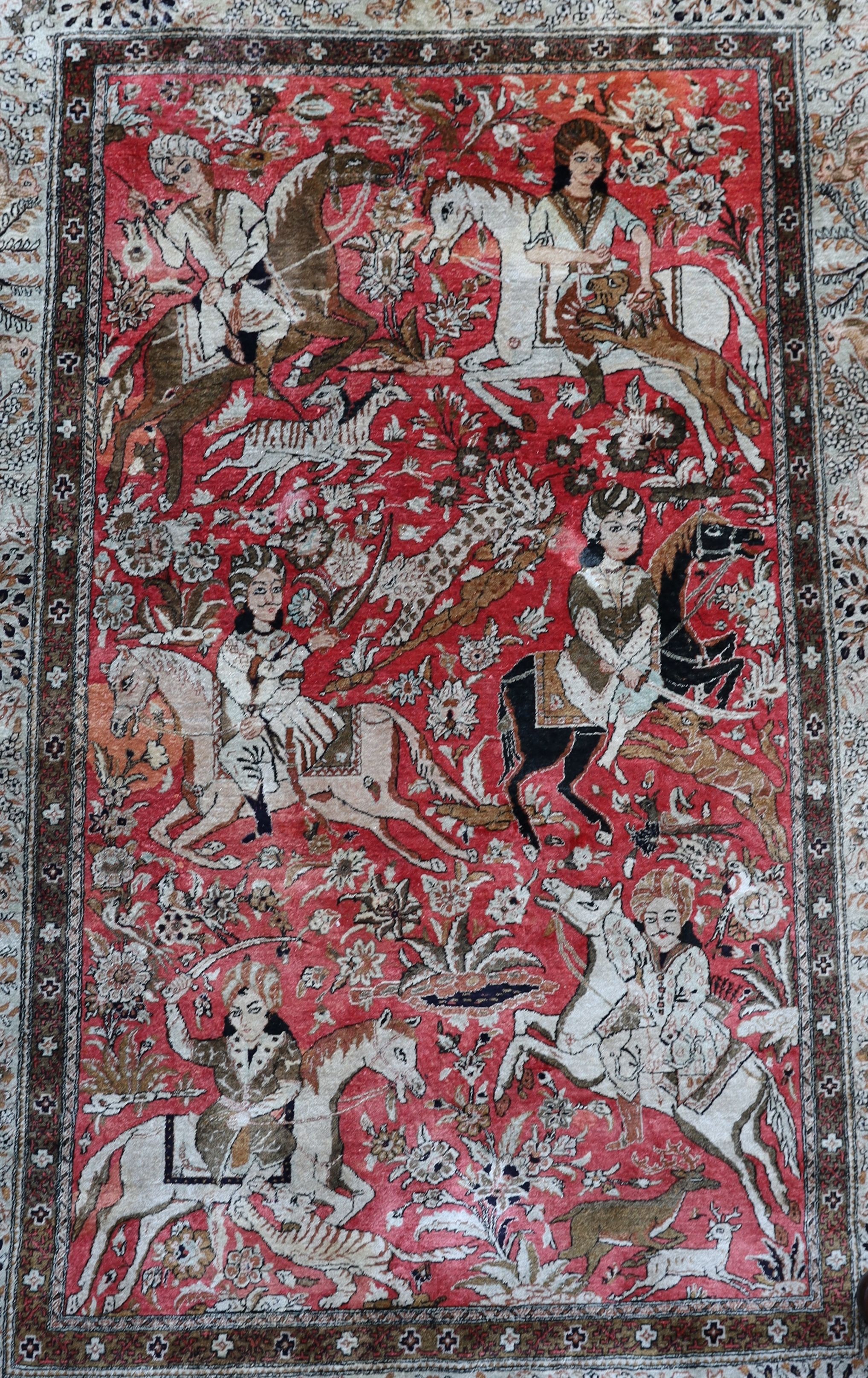 An early 20th century Tabriz pictorial red ground rug, woven with hunters on horseback, 208 x 135cm.